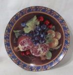 PORCELANA - Um prato decorativo em porcelana vitrificada branca, ricamente pintado à mão, decorado com frutos e folhas em exuberante policromia, com bordas filetadas à ouro, assinado "Bia" no fundo, medindo: 24 cm de diâmetro. Vide fotos.