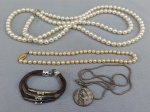 BIJUTERIAS, quatro (4) itens distintos: 1 pulseira em metal com três voltas de tonalidades variadas, fecho do tipo lobster, apliques em strass; 1 cordão em metal prateado com fecho do tipo boia, medindo 62 cm comprimento, fora pingente sacro relevado com as imaginárias de Santa Clara e São Francisco de Assis; 1 gargantilha com imitações de pérolas (duas delas descascando), fecho em metal dourado, medindo 39 cm comprimento; 1 colar confeccionado com imitações de pérolas, fecho rosqueável em metal prateado, medindo 134 cm.