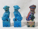 ESCULTURAS - Três esculturas em porcelana vitrificada, sendo duas na cor azul e uma ricamente policromada, representando Cão de Fó, sobre base em forma de bloco retangular. Medidas aproximadas: 20 cm de altura x 7 cm de comprimento da base x 5,5 cm de largura da base. Dois possui diversos colados, conforme fotos extras.