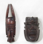 ARTE AFRICANA - Dois adornos de parede em madeira ricamente entalhada, representando cabeças de figuras africanas. Medidas: maior: 17 cm de altura/ menor: 11 cm de altura.