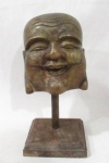 ESCULTURAS - Escultura em madeira, ricamente entalhada e patinada com toques de folhas de ouro velho, representando Cabeça de Buda, sobre base em formato retangular. Med. alt 18,5 cm x comp da base 9,5 cm x larg da base 9 cm, aproximadamente.