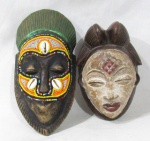 ARTE AFRICANA - Duas máscaras africanas esculpidas em madeira patinada, sendo uma ricamente ornamentada com miçangas em policromia e búzios, e uma representando Povo Punu. Medidas: maior: 23 cm de altura x 11 cm de largura/ menor: 16 cm de altura x 10 cm de largura. Vide fotos.