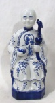 ESCULTURAS - Escultura Oriental em porcelana vitrificada nas tonalidades branca e azul, representando Imperatriz Chinesa, ricamente ornamentada com motivos vegetalistas e volutas. Med. alt 30 cm x comp da base 12 cm x larg da base 11 cm.
