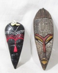 ARTE AFRICANA - Duas máscaras africanas, sendo uma em madeira patinada ornamentada com placas em metal cinzelado, e uma em barro cozido policromado com adereço de búzios. Medidas: maior: 29 cm de altura/ menor: 22,5 cm de altura. Vide fotos.