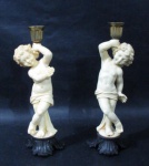 CANDELABRO / CASTIÇAL - Dois graciosos castiçais para uma vela, confeccionados em resina, com bobeche em metal dourado, seguido de coluna com escultura barroca italiana representando Putino, sobre base finalizando com folhas de acanto negras, medindo: alt 21 cm x larg da base 6,5 cm.