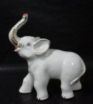 ESCULTURAS - Elefante em porcelana vitrificada branca, arrematado com filetes e faixas em pintura á ouro, medindo: alt 20,5 cm x comp 17 cm, aproximadamente.
