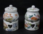 PORCELANA - Dois conjuntos de molheiras com réchauds em porcelana vitrificada branca, decorados com motivos vegetalistas em rica policromia, pega da tampa em formato esférico, base adornada com corações vazados. Medidas totais: alt 12 cm x diam da borda 6 cm. Possui etiqueta com a inscrição MADE IN CHINA em suas bases. Vide fotos extras!