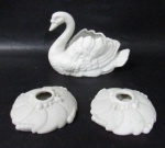 DIVERSOS - Lote contendo três (3) peças em biscuit, trabalhado em feitios distintos, sendo um vaso floreira em formato de pato, e um par de castiçais para uma vela retratando flor. Med. maior: alt 11,5 cm x comp 15,5 cm/ menor: diam da base 9 cm.