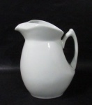 PORCELANA -Diferenciada jarra para água/ suco em porcelana vitrificada branca, moldada em formato bojudo, com bico e alça estilizados, medindo: alt 23 cm x larg total 20 cm.