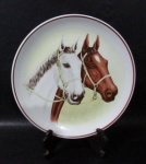 PORCELANA SCHMIDT - Um prato decorativo, de coleção, em porcelana vitrificada branca, decorada com figuras de cavalos em policromia ao centro, bordas adornadas com filetes na tonalidade marrom, marcado no fundo, medindo: 25,8 cm de diâmetro.
