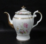 PORCELANA REAL S. PAULO - Um bule para café em porcelana vitrificada branca, decorado com motivos vegetalistas em suave policromia ao centro, adornado com guirlandas de folhas e arabescos dourados, bordas movimentadas e generosamente filetadas à ouro, pega da tampa em forma estilizada, alça finalizando em voluta e bico arrematados com vasta douração, marcado no fundo. Med.: alt total 20 cm x larg total 23 cm. Em ótimo estado!