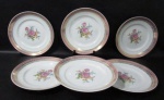 PORCELANA SCHMIDT - Seis pratos rasos em porcelana vitrificada branca, decorados com motivos florais em rica policromia ao centro, seguido de bordas adornadas com guirlandas de folhas e arabescos, generosos filetes e gregas em pintura à ouro, sobre faixa esmaltada na tonalidade rosa. Med. 24,5 cm de diâmetro. Um com fio de cabelo e ínfimo bicado na borda, conforme foto extra.