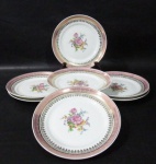 PORCELANA SCHMIDT - Sete pratos para sobremesa em porcelana vitrificada branca, decorados com motivos florais em rica policromia ao centro, seguido de bordas adornadas com guirlandas de folhas e arabescos, generosos filetes e gregas em pintura à ouro, sobre faixa esmaltada na tonalidade rosa, marcados no fundo. Med. 18,2 cm de diâmetro. Um com fio de cabelo na borda