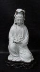 ESCULTURAS - Belíssima escultura em porcelana oriental vitrificada branca, ricamente detalhada representando "Deusa Kuan Yin", apoiada sobre peanha em madeira, marcada com caracteres no fundo. Medidas totais: alt 35 cm x comp da base 21,5 x larg da base 19,5 cm.