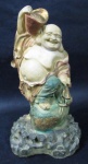 ESCULTURA - Escultura confeccionada em resina, ricamente detalhada e policromada, representando "Buda da Fortuna", medindo: 23 cm de altura x 12,5 de comprimento da base.