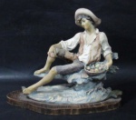 ESCULTURAS - Belíssima escultura em resina italiana, ricamente detalhada e policromada, representando "Cavalheiro sentado segurando cesta de frutos", sobre base de madeira em formato oval, assinatura não identificada. Medidas alt 22 cm x comp da base 27 cm x larg da base 13,5 cm.