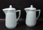 PORCELANA - Par de antigas leiteiras elétricas, em porcelana vitrificada na tonalidade azul bebê, bojo ricamente trabalhado em canelados, pega da tampa em forma estilizada de pinha, alças vazadas, medindo: alt total 23 cm x larg total 18 cm. Não testadas e sem garantias de funcionamento.