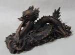 ESCULTURAS - Escultura em resina esmaltada em nuances negras, ricamente detalhada, representando "Dragão", medindo: alt 11,5 cm x comp da base 24 cm x larg da base 8,5 cm. Possui bicado e ínfimos bicados.