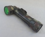 MILITARIA, uma (1) lanterna, modelo TL-122, dito cotovelo, também conhecida na caça e pesca como lanterna farolete, tonalidade camuflada, confeccionada em materiais diversos, a pilha, funcionamento não testado, usada e sem garantia, medindo 21 cm.
