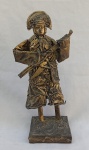 PAULO GOMES, uma (1) escultura representando cangaceiro, confeccionada em papel machê, base em madeira e patina na tonalidade bronze, assinada na base, medindo 29 cm altura.