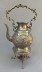 METAL PRATEADO, um (1) samovar em duas partes, bule e trempe de apoio, faltam a tampa e o queimador, ornamentação cinzelada em volutas e elementos vegetalistas, não possui marca de manufatura aparente, medindo 38 cm altura.