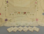 CAMA E MESA, uma (1) toalha de mesa quadrangular, confeccionada em tecido de algodão na tonalidade creme, com bordado floral policromado, medindo 145 x 145 cm, acompanham 6 guardanapos na mesma padronização, medindo 20 x 20 cm, usada e com manchas.