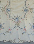 CAMA E MESA, uma (1) toalha de mesa quadrangular, ILHA DA MADEIRA, confeccionada em linho na tonalidade creme, com crivo e bordado policromado, medindo 130 x 130 cm, usada e com manchas.
