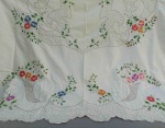 CAMA E MESA, uma (1) toalha de mesa, confeccionada em tecido de algodão na tonalidade branca, com bordado floral policromado, medindo 220 x 180 cm, usada e com manchas.