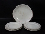 FAIANÇA - CREAMPETAL GRINDLEY ENGLAND - Um prato para bolo com oito pratinhos, em faiança inglesa vitrificada na cor creme, ornados com frisos na tonalidade vermelha, bordas ligeiramente onduladas e filetadas à ouro, marcados no fundo. Med.: maior: 24 cm de diâmetro/ menor: 17,5 cm de diâmetro. Prato para bolo com pequenas marcas do tempo e um pratinho com ínfimo bicado na borda.