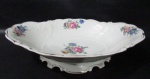 PORCELANA - KPM - Uma fruteira em fina porcelana polonesa vitrificada branca, trabalhada com folhas e volutas sutilmente relevadas, decorada com motivos vegetalistas em rica policromia, bordas e base recortadas, arrematada com filetes de resquícios à ouro, marcada no fundo. Med. alt 8 cm x comp 32 cm x larg 23,5 cm.