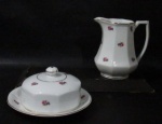 PORCELANA - MAUÁ - Uma leiteira e uma manteigueira em porcelana nacional vitrificada branca, moldadas em formato geometrizado, delicadamente decoradas com motivos florais em policromia, alça vazada, pega da tampa em feitio de botão de flor, bordas filetadas à ouro, marcadas no fundo. Med. maior: alt 13 cm x larg total 12,5 cm/ menor: alt total 7,5 cm x diam total 15 cm.