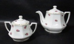 PORCELANA - MAUÁ - Um bule e um açucareiro em porcelana nacional vitrificada branca, moldados em formato geometrizado, delicadamente decoradas com motivos florais em policromia, alças vazadas, pegas das tampas em feitio de botão de flor, bordas filetadas à ouro, marcados no fundo. Med. maior: alt total 13 cm x larg total 18,5 cm/ menor: alt total 9,5 cm x larg total 13,5 cm.