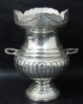 METAL - Elegante floreira em metal espessurado à prata decorada com gomos e caneluras, bordas onduladas e marchetadas em volutas , alças vazadas apoiada sobre pé bolacha. Medida altura 22 cm X largura 19 cm,