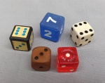 BRINQUEDO, cinco (5) dados variados, confeccionados em materiais diversos, medindo o maior deles 2,2 x 2,2 x 2,2 cm.