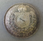 NUMISMÁTICA, Brasil, Império, uma (1) moeda, 2000 reis 1889, prata (900/916 milésimos), 3 sistema monetário, 4 tipo, 25,5gr, 37mm diâmetro, 2,7mm espessura, bordo serrilhado, 2 reinado, D. Pedro II, muito bom estado de conservação, anverso: Efígie de D. Pedro II, na orla a legenda PETRUS II D. G. C. IMP. ET PERP. BRAS. DEF. e o ano de cunhagem realizada à época na Província do Rio de Janeiro; reverso: no enxergo brasão do império na orla o dístico do valor de face e o DECRETO DE 1870, batidinhas na serrilha.