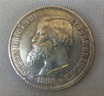 NUMISMÁTICA, Brasil, Império, uma (1) moeda, 2000 reis 1888, prata (900/916 milésimos), 3 sistema monetário, 4 tipo, 25,5gr, 37mm diâmetro, 2,7mm espessura, bordo serrilhado, 2 reinado, D. Pedro II, muito bom estado de conservação, anverso: Efígie de D. Pedro II, na orla a legenda PETRUS II D. G. C. IMP. ET PERP. BRAS. DEF. e o ano de cunhagem realizada à época na Província do Rio de Janeiro; reverso: no enxergo brasão do império na orla o dístico do valor de face e o DECRETO DE 1870.