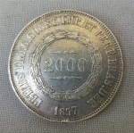 NUMISMÁTICA, Brasil, Império, uma (1) moeda, 2000 reis 1857 (DATA ESCASSA), prata (900/916 milésimos), 3 sistema monetário, 2 tipo, 25,5gr, 37mm diâmetro, 2,7mm espessura, bordo serrilhado, 2 reinado, D. Pedro II, muito bom estado de conservação, anverso: dístico do valor de face, circundado por guirlanda de tulipas, na orla a legenda PETRUS II D. G. CONST. IMP. ET PERP. BRAS. DEF., seguido do ano de cunhagem feita a época na Província do Rio de Janeiro; reverso: no enxergo brasão do império encimado pela legenda IN HOC SIGNO VINCES.