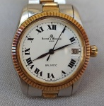 RELÓGIO, um (1) antigo de pulso, marca BAUME & MERCIER (fundada em 1830 como FRERES BAUME, pelos irmãos Louis-Victor Baume e Celestin Baume; em 1851 abriu uma filial em Londres com o nome BAUME BROTHERS; em 1918 o diretor da empresa William Baume fez parceria com Paul Mercier e virou BAUME & MERCIER; em 1919 recebeu o selo de Genebra (alta distinção por excelência em relojoaria); em 1988 ingressou no Grupo Richemont, ainda em funcionamento), Suíço, mostrador branco com algarismos romanos, possui calendário, modelo BAUMATIC, caixa, tampa e pulseira em aço escovado com detalhes em dourado, medindo 30 mm diâmetro, funcionando, usado e sem garantia.