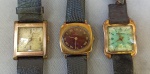 RELÓGIOS, três (3) de pulso distintos, todos mecânicos e com 17 rubis ou safiras: 1 da marca BUCHERER (relojoaria Suíça fundada em 1888 por Carl Friedrick Bucherer, ainda em funcionamento, já com a quarta geração da família), mostrador vermelho com algarismos romanos, parado, medindo 23 x 23 mm, caixa em metal dourado, tampa em aço, pulseira em couro; 1 da marca MONDAINE (Mondaine Watch Ltd., relojoaria fundada em 1944, por Hans Hilfiker, em Zurique, Suíça), parado, mostrador com algarismos arábicos, caixa em metal dourado, tampa em aço, medindo 27 x 22 mm, pulseira no estado; 1 da marca MILUS (fundada em 1919 por Paul William Junod, estabelecida à época na Route de Reuchenette 21, Biel, Suíça; em 1951 assume o filho Paul Herbert Junod; em 1982 assumem os netos Paul Junod e Pierre Junod; em 2003 foi vendida para Peace Mark Group; em 2008 foi vendida para Chow tai Fook; em 2016 foi vendida para Tissot), funcionando, caixa em metal dourado, medindo 27 x 22 mm, tampa em aço, pulseira em couro se desfazendo, todos usados e sem garantias.