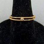 JOIA, uma (1) aliança dupla, detalhes em torçaide, com um diamante lapidação brilhante com aproximadamente 1 ponto, confeccionada em OURO amarelo, contrastado 750 K e marca de ourives não identificada, tamanho 15, peso 1,1 gr.