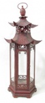 DIVERSOS - LATÃO - Antiga lanterna para vela em latão patinado de vermelho, ricamente trabalhado retratando Pagode Chinês, parte central com vidro translúcido. Medidas: 60 cm de altura x 20,5 cm de comprimento da base x 17,8 cm de largura da base. Possui uma morsa na base.