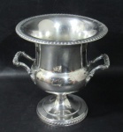 METAL - Champanheira em metal espessurado à prata bojo liso, alças vazadas adornada com gomos e caneluras apoiada sobre pé circular. Apresenta pequena mossa no bojo.  Medida 25 cm X 23 cm.