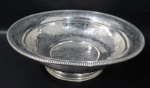 METAL - Elegante bacia de gomil em metal espessurado à prata parte central decorada com folhas e flores bordas marteladas e gomadas, apoiada sobre pé circular. Banho novo. Medida 40 cm X 13 cm.