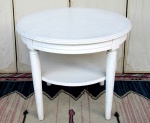 MOBILIÁRIO, uma (1) mesa redonda de apoio, confeccionada em madeira e placagem com patina na tonalidade branca, tampo com borda em degrau, quatro pés torneados com amarração em cubo, caneluras verticais e afinando para baixo, possui prateleira de amarração, sinais de uso, medindo 52 x 60 cm.