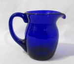 CRISTAIS HERING - Jarra d'água/ refresqueira em cristal manufaturado Hering, na cor azul cobalto, seguido de alça vazada. Medidas: 17 cm x 20 cm.