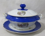 PORCELANA - REAL S. PAULO - Uma sopeira com presentoir em porcelana nacional vitrificada branca, apresentando cena galante em rica policromia ao centro, seguida de friso dourado, bordas ligeiramente onduladas e adornadas com larga faixa na tonalidade azul, finalizando com filetes em pintura à ouro, pega da tampa em formato de flor, alças trabalhadas em folhas, marcadas no fundo. Med. sopeira: alt total 19 cm x larg total 33 cm/ presentoir; diam 32 cm. Sopeira possui pequenas falhas na douração.