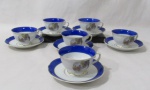 PORCELANA - REAL S. PAULO - Seis xícaras para chá com seus respectivos pires, em porcelana nacional vitrificada branca, apresentando cena galante em rica policromia ao centro, seguida de friso dourado, bordas ligeiramente onduladas e adornadas com larga faixa na tonalidade azul, finalizando com filetes em pintura à ouro, alças trabalhadas em folhas com vasta douração, apoiadas sobre pé bolacha, marcados no fundo. Med.. xícaras: alt 5,5 cm x diam 9,3 cm/ pires: diam 14,5 cm.