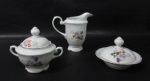 PORCELANA REAL S. PAULO - Um açucareiro, uma leiteira e uma manteigueira em porcelana vitrificada branca, delicadamente decorados com motivos vegetalistas em exuberante policromia, bordas movimentadas e filetadas à ouro, pegas das tampas em forma estilizada de flor, alças vazadas finalizando em volutas, marcados no fundo. Medidas: maior: alt 15 cm x larg total 16 cm/ menor: alt total 9 cm x diam total 14 cm. Tampa do açucareiro com bicado na parte interna da borda.