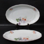 PORCELANA REAL S. PAULO - Duas travessas ovaladas em porcelana vitrificada branca, com tamanhos distintos, delicadamente decoradas com motivos vegetalistas em exuberante policromia, bordas movimentadas e filetadas à ouro, marcadas no fundo. Medidas: maior: comp 33 cm x larg 20 cm/ menor: comp 29 cm x larg 18 cm. Ambas possui bicados nas bordas. Vide fotos extras!