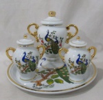 PORCELANA - BELA VISTA - Três potiches de tamanhos distintos e uma bandeja redonda, em porcelana vitrificada branca, ornamentados com pavões e motivos vegetalistas em exuberante policromia, adornados com faixas e filetes em pintura à ouro, pegas das tampas  e alças laterais com vasta douração, marcados no fundo. Medidas: maior: alt total 19 cm x larg total 17,5 cm/ menor: diam 29 cm.